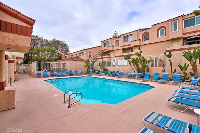 pool with fence, a patio, and a residential view