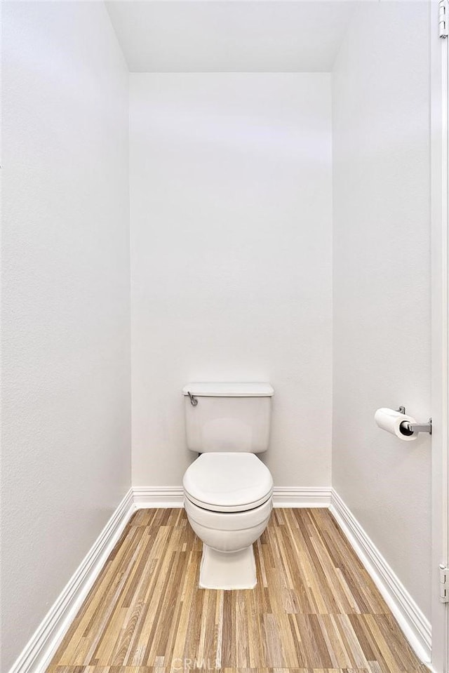 bathroom featuring toilet, baseboards, and wood finished floors
