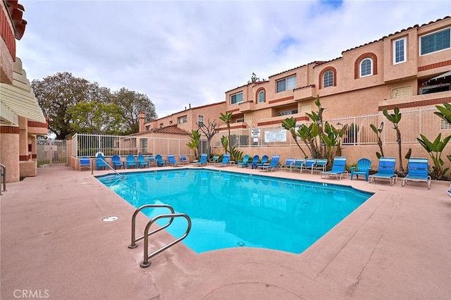 community pool with fence, a patio area, and a residential view