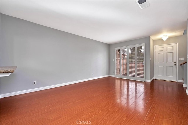 unfurnished living room featuring baseboards, visible vents, and wood finished floors