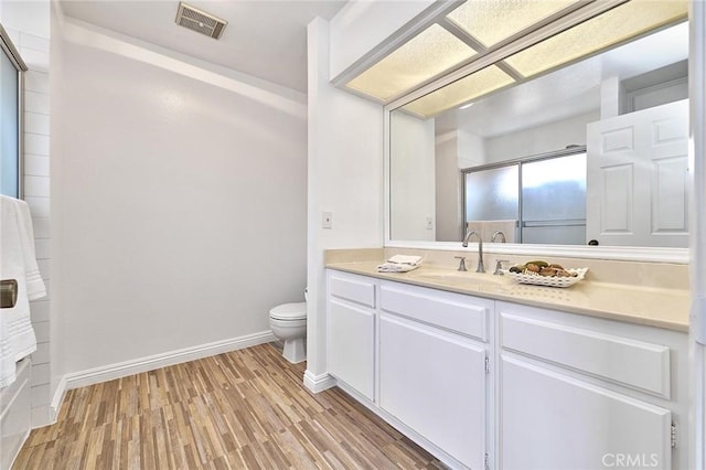 full bathroom featuring vanity, toilet, baseboards, wood finished floors, and visible vents