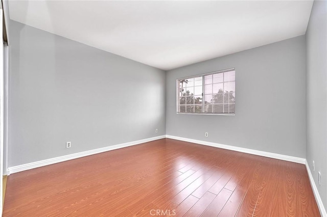 spare room featuring baseboards and wood finished floors