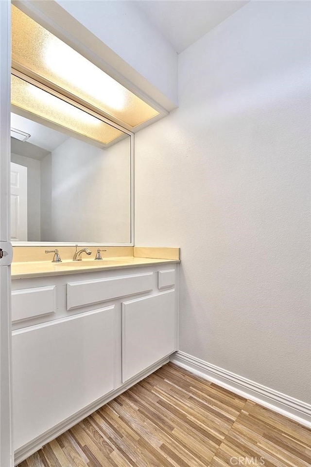 bathroom featuring baseboards, wood finished floors, and vanity