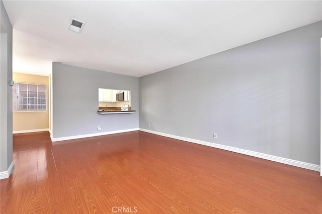 spare room featuring baseboards, visible vents, and wood finished floors
