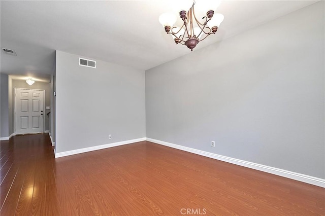 unfurnished room with baseboards, a chandelier, dark wood finished floors, and visible vents