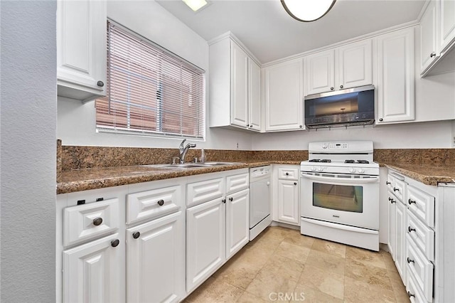 kitchen featuring dark countertops, a sink, white appliances, and white cabinetry