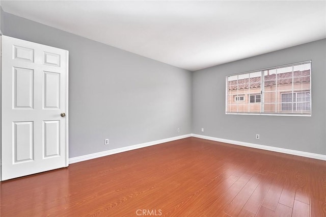 unfurnished room with baseboards and wood finished floors