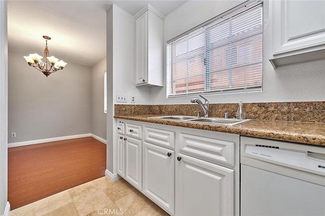 kitchen featuring white cabinets, dark countertops, a notable chandelier, a sink, and dishwasher