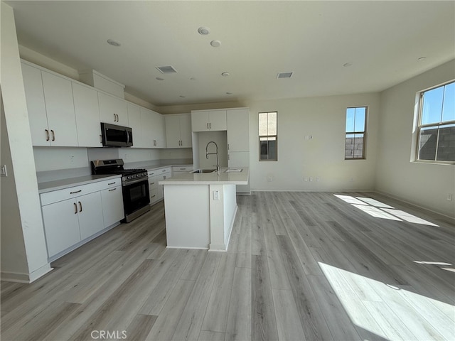15893 Blue Copper Way, Fontana, CA 92336 - kitchen with appliances with stainless steel finishes, a sink, light wood finished floors, white cabinetry, and a center island with sink