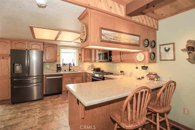 kitchen with a peninsula, a sink, stainless steel appliances, a kitchen breakfast bar, and light countertops