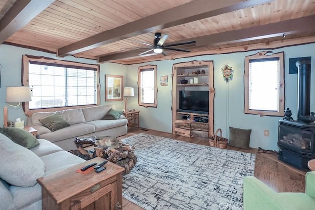 living area featuring beamed ceiling, a wood stove, and wood ceiling