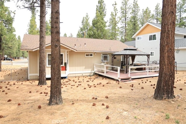 rear view of house with a shingled roof, a gazebo, and a deck