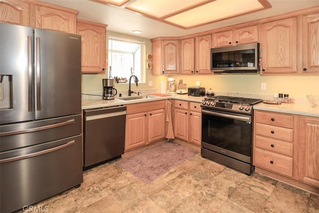 kitchen with light brown cabinetry, appliances with stainless steel finishes, and a sink