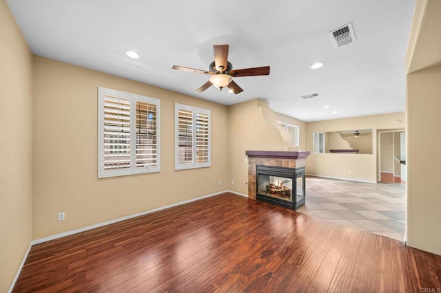 unfurnished living room with visible vents, a ceiling fan, and a multi sided fireplace