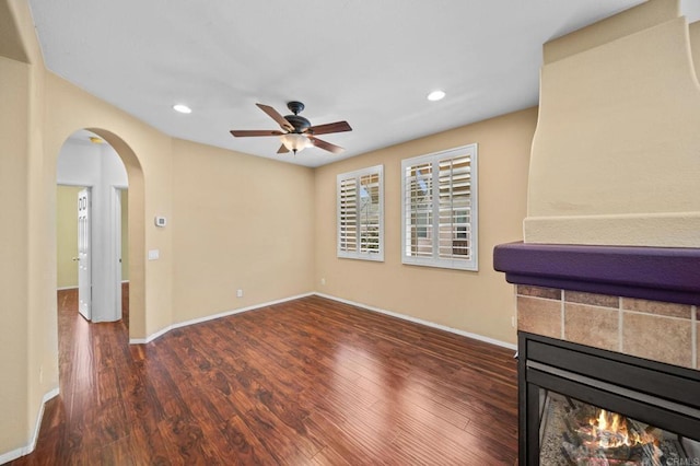 unfurnished living room featuring arched walkways, a ceiling fan, recessed lighting, and wood finished floors