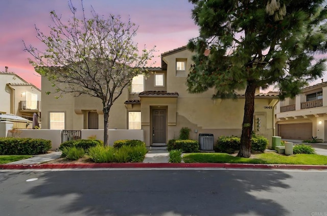 view of front of property featuring fence, central AC unit, stucco siding, and a tiled roof