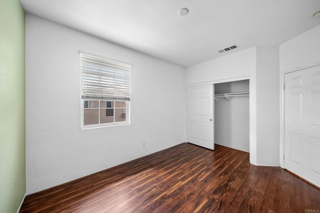 unfurnished bedroom featuring a closet, dark wood-style flooring, and visible vents
