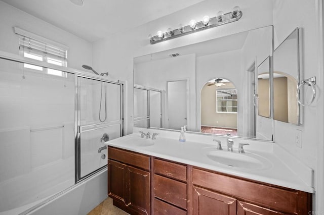 bathroom featuring a sink, bath / shower combo with glass door, double vanity, and visible vents
