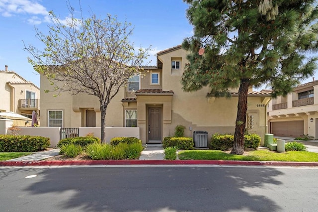 view of front of house featuring cooling unit, stucco siding, a tiled roof, and fence