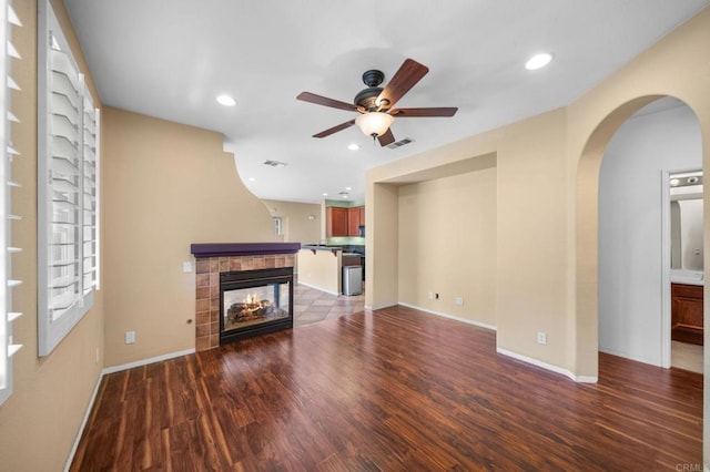 unfurnished living room featuring arched walkways, ceiling fan, visible vents, and wood finished floors
