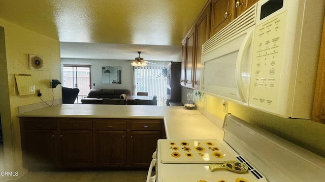 kitchen featuring a ceiling fan, light countertops, a peninsula, open floor plan, and white appliances