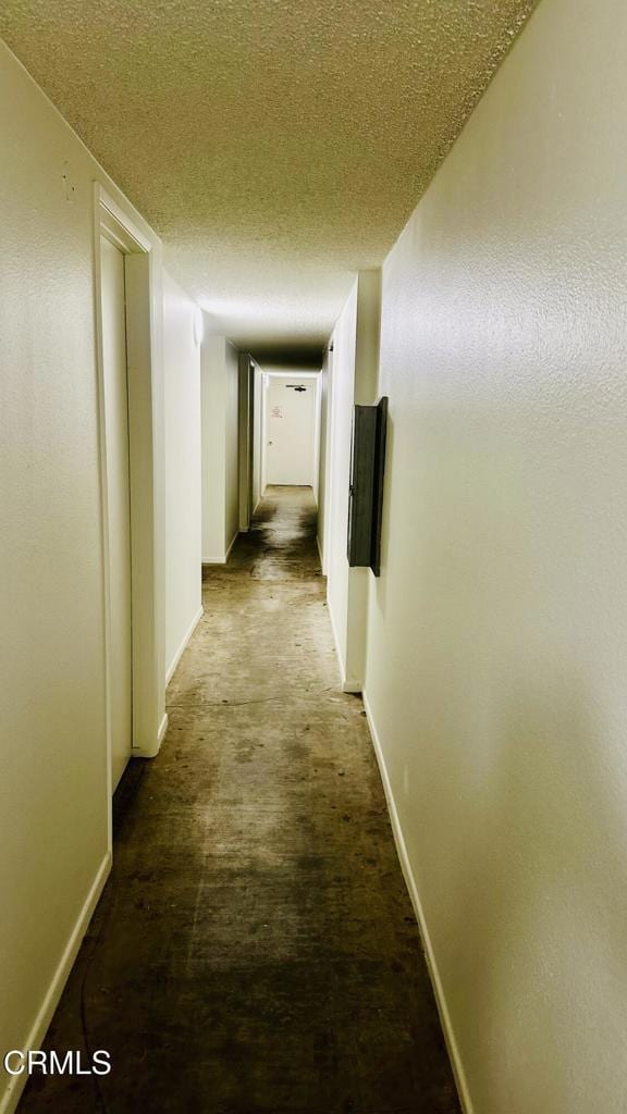 corridor featuring a textured ceiling and baseboards
