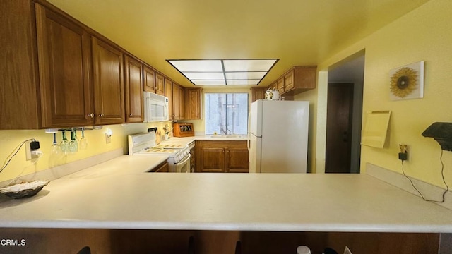 kitchen with brown cabinetry, light countertops, a sink, and white appliances