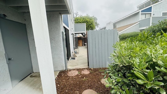 view of side of property featuring stucco siding and fence