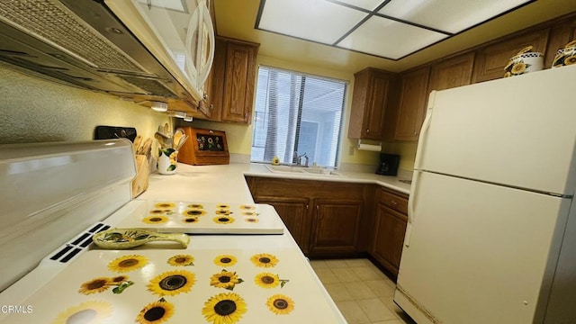 kitchen with light countertops, freestanding refrigerator, and a sink