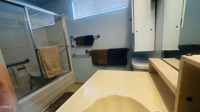 bathroom featuring baseboards, toilet, shower / bath combination with glass door, and vanity