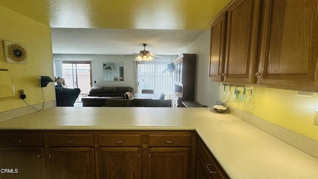 kitchen featuring light countertops, a ceiling fan, a peninsula, and open floor plan