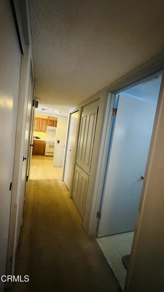 hallway with a textured ceiling and light colored carpet