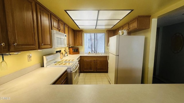 kitchen with a sink, light countertops, white appliances, and light floors