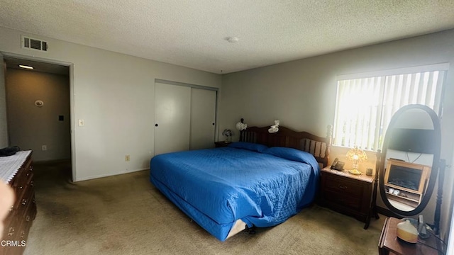 bedroom featuring visible vents, a textured ceiling, carpet, and a closet