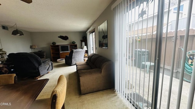 living area featuring a textured ceiling, light colored carpet, ceiling fan, and visible vents