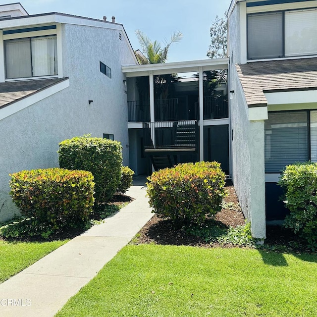 view of property exterior with a sunroom, stucco siding, and a yard