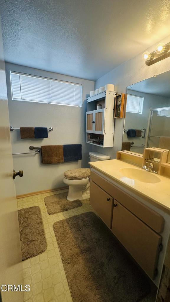bathroom featuring a textured ceiling, an enclosed shower, tile patterned floors, vanity, and toilet