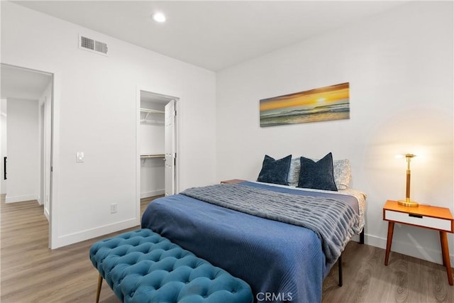 bedroom featuring recessed lighting, baseboards, wood finished floors, a spacious closet, and visible vents