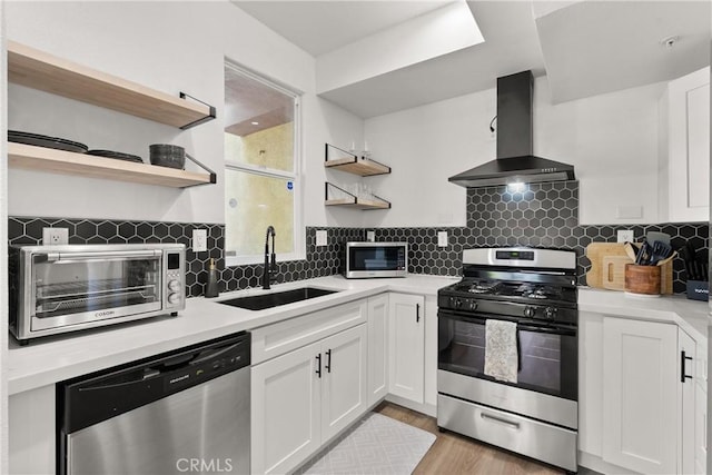 kitchen featuring wall chimney range hood, open shelves, a sink, stainless steel appliances, and a toaster