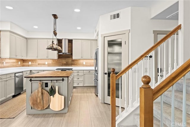26544 Mahonia Way, Murrieta, CA 92562 - kitchen featuring appliances with stainless steel finishes, wall chimney range hood, butcher block countertops, decorative backsplash, and pendant lighting