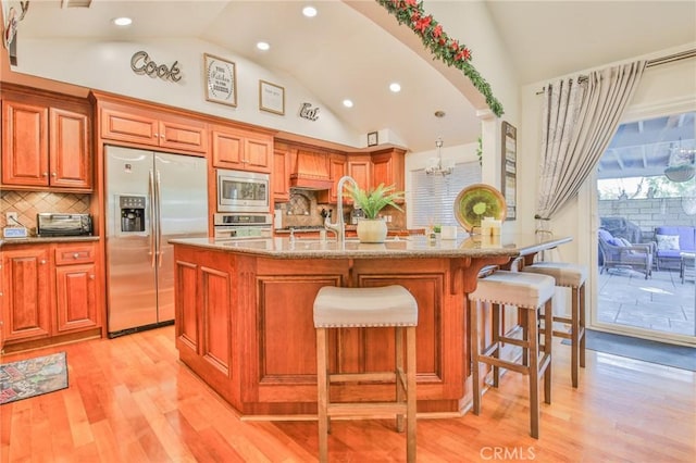 kitchen featuring decorative backsplash, recessed lighting, light stone counters, light wood finished floors, and stainless steel appliances