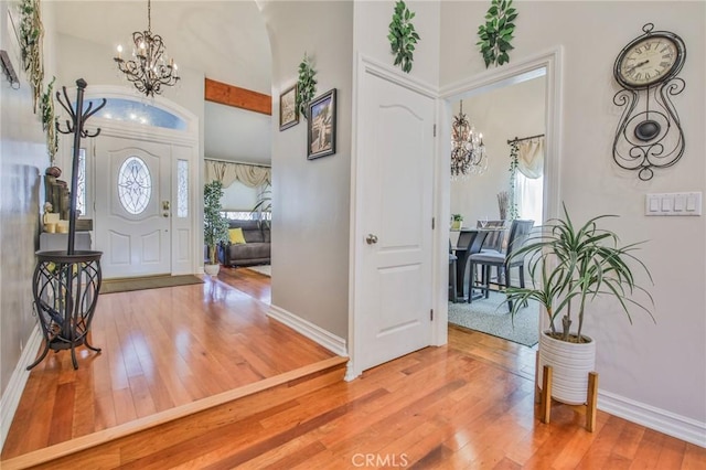 entrance foyer with an inviting chandelier, baseboards, a towering ceiling, and hardwood / wood-style flooring