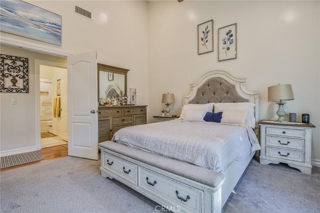 bedroom featuring connected bathroom, baseboards, visible vents, and carpet