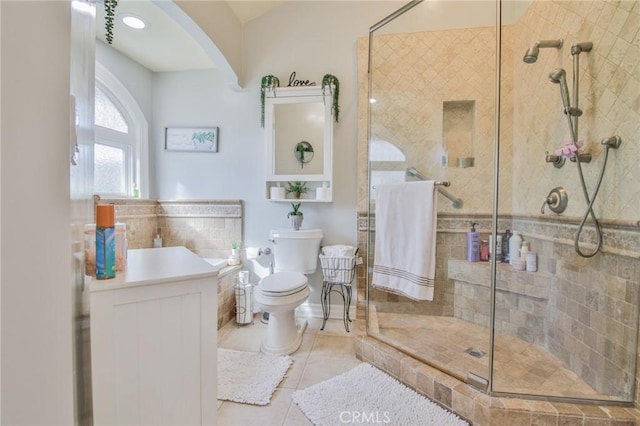 bathroom featuring vanity, toilet, tile walls, tile patterned floors, and a stall shower