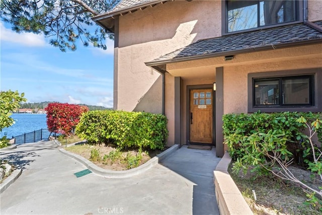 entrance to property featuring a water view and stucco siding