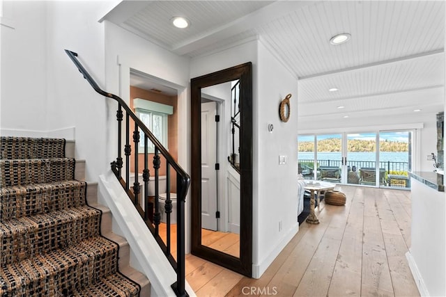 stairway with a water view, baseboards, recessed lighting, and hardwood / wood-style floors