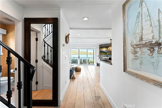 corridor with recessed lighting, baseboards, stairs, and light wood-style flooring