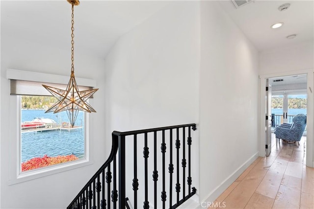 hallway featuring visible vents, an inviting chandelier, lofted ceiling, baseboards, and light wood-type flooring