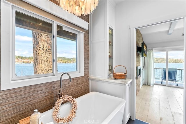 full bathroom with a soaking tub, plenty of natural light, a sink, and a water view