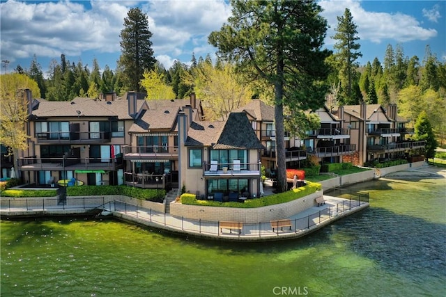 rear view of property featuring a water view, a residential view, and stucco siding